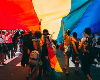 groupe de personnes tenant un drapeau arc-en-ciel