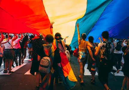 groupe de personnes tenant un drapeau arc-en-ciel