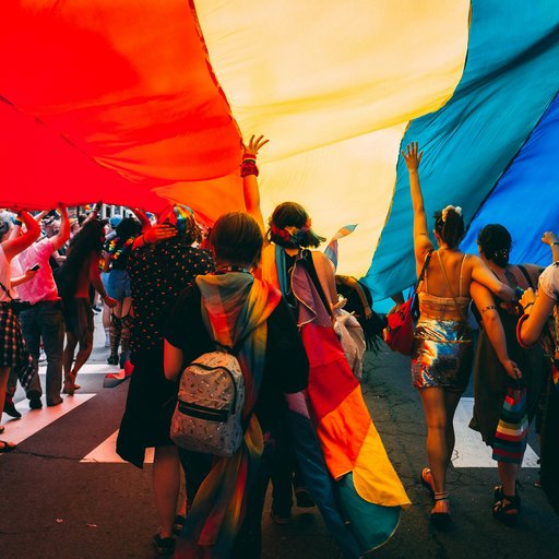 groupe de personnes tenant un drapeau arc-en-ciel