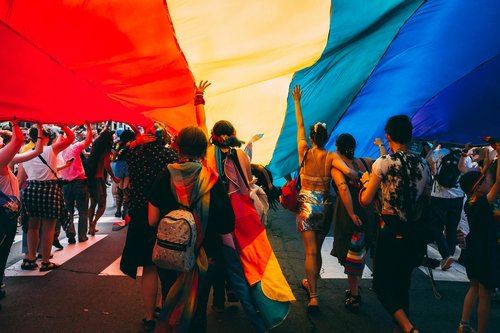 groupe de personnes tenant un drapeau arc-en-ciel